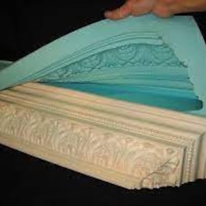 May include: A teal silicone mold for making decorative plaster or resin moldings. The mold is flexible and shows the detailed design of the molding.