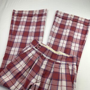 以下が含まれることがあります： ピンク、白、青のチェック柄のワイドレッグパンツ。パンツはフロントにプリーツがあり、ボタン留めです。