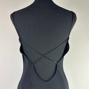 May include: Black sleeveless maxi dress with a low back and criss-cross straps.