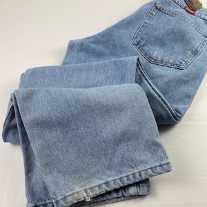 May include: A pair of light blue denim jeans with a Wrangler logo patch on the back pocket.
