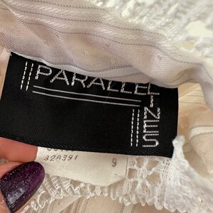 May include: A white, striped, sheer top with a white lace trim. The label reads "PARALLEL" and "UNIQLO" with the number "328391" and "9" visible.