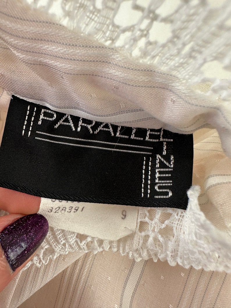 May include: A white, striped, sheer top with a white lace trim. The label reads "PARALLEL" and "UNIQLO" with the number "328391" and "9" visible.