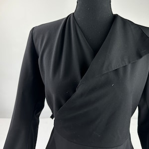 May include: A black long-sleeved wrap dress with a deep V-neckline and a collar.