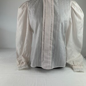 May include: A white sheer blouse with a high collar and long sleeves. The collar and cuffs have lace trim. The blouse has vertical stripes.