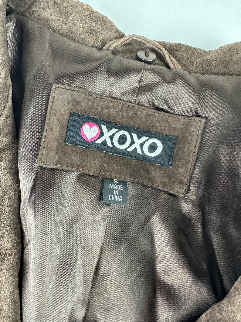 May include: Brown suede jacket with a black label that says "XOXO" with a pink heart. The label also says "Made in China" and "S".