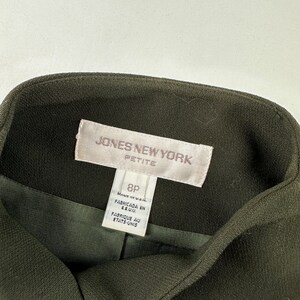 May include: A green blazer with a white label that reads "JONES NEW YORK PETITE" and "8P MADE IN U.S.A. FABRICADA EN E.E.U.U. FABRIQUE AU ETATS-UNIS".