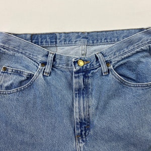 May include: A pair of light blue denim jeans with a button fly and five pockets.