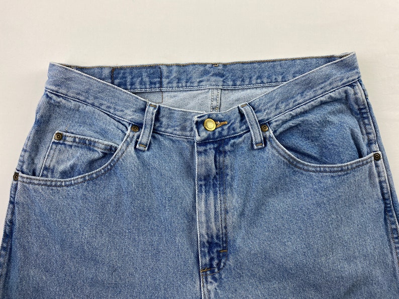 May include: A pair of light blue denim jeans with a button fly and five pockets.