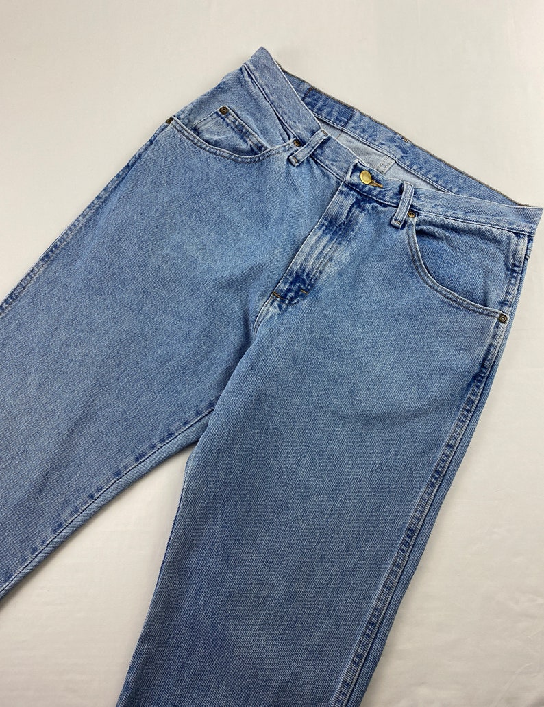 May include: Light blue denim jeans with a classic five-pocket style. The jeans have a straight leg and a button fly.