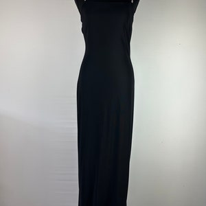 May include: A black maxi dress with thin straps and a square neckline. The dress has a simple, elegant design.