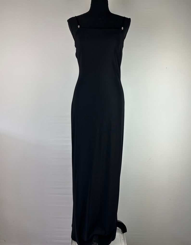 May include: A black maxi dress with thin straps and a square neckline. The dress has a simple, elegant design.
