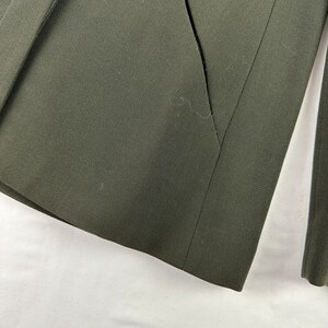 May include: A dark green blazer with a single pocket on the left side. The blazer is made of a smooth, textured fabric.