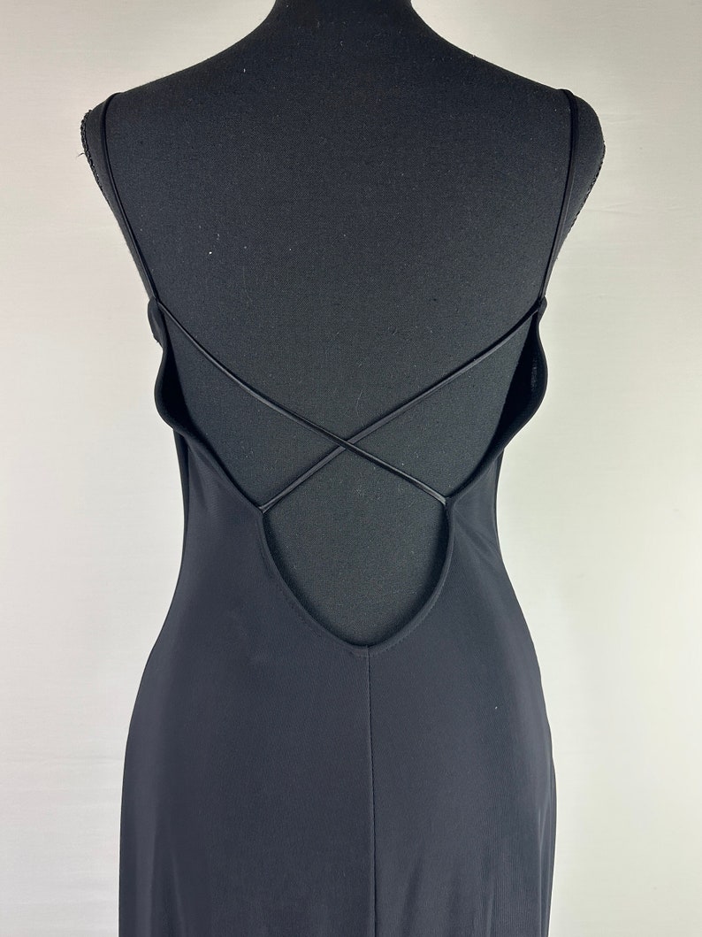 May include: Black sleeveless maxi dress with a low back and criss-cross straps.