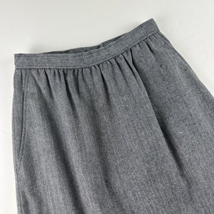 May include: A gray skirt with a herringbone pattern. The skirt has a waistband and a gathered front.