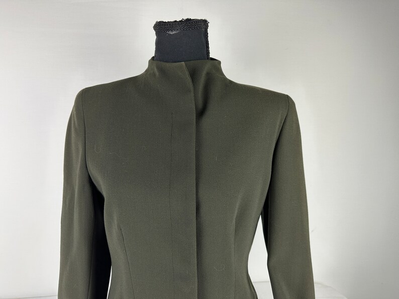 May include: A dark green blazer with a high collar and a single button closure.