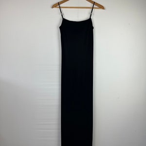 May include: A black maxi dress with thin straps hanging on a wooden hanger against a white background.