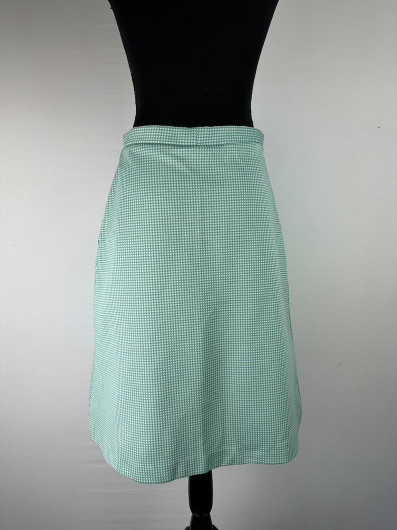 May include: A green and white gingham skirt with a straight silhouette. The skirt is knee-length and has a simple design.