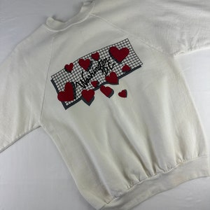 May include: White sweatshirt with a red and black graphic print that says "Washington D.C." surrounded by red hearts.