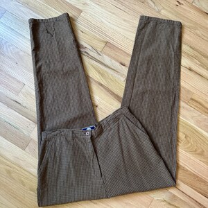 May include: Brown and black plaid pants with a button closure and a single front pocket.