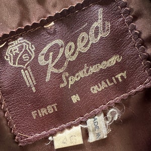 May include: A brown leather label with the text "Reed Sportswear First in Quality" in gold lettering. The label has a decorative scalloped edge.