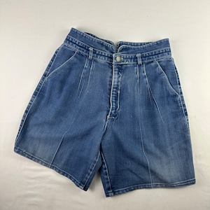 May include: A pair of blue denim shorts with a high waist and pleats. The shorts have a button and zipper closure.