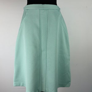 May include: A green and white gingham skirt with a straight, A-line silhouette. The skirt has a center seam and a simple, fitted waistband.
