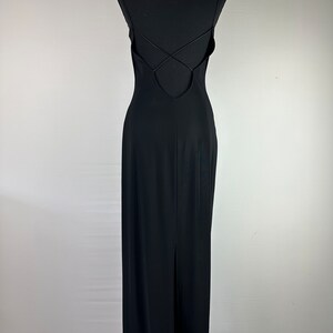 May include: A black maxi dress with a low back and spaghetti straps. The straps cross in the back and the dress has a slit in the back.