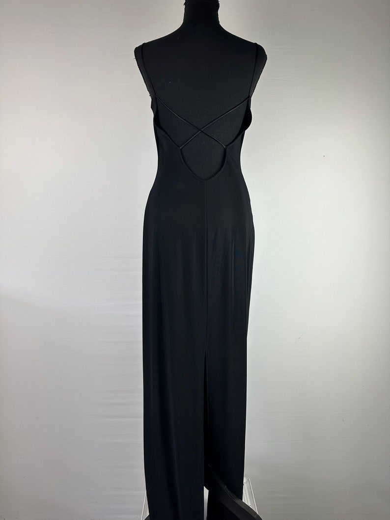 May include: A black maxi dress with a low back and spaghetti straps. The straps cross in the back and the dress has a slit in the back.