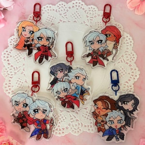 Könnte beinhalten: Fünf durchsichtige Acryl-Schlüsselanhänger mit Chibi-Anime-Figuren in farbenfrohen Outfits und Accessoires. Jeder Anhänger hat einen roten oder blauen Karabinerverschluss. Die Motive zeigen verschiedene Charakter-Paarungen und Gruppen in Posen.