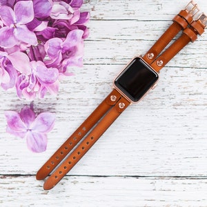 May include: A brown leather double-wrap watch band with rose gold hardware and a black watch face.