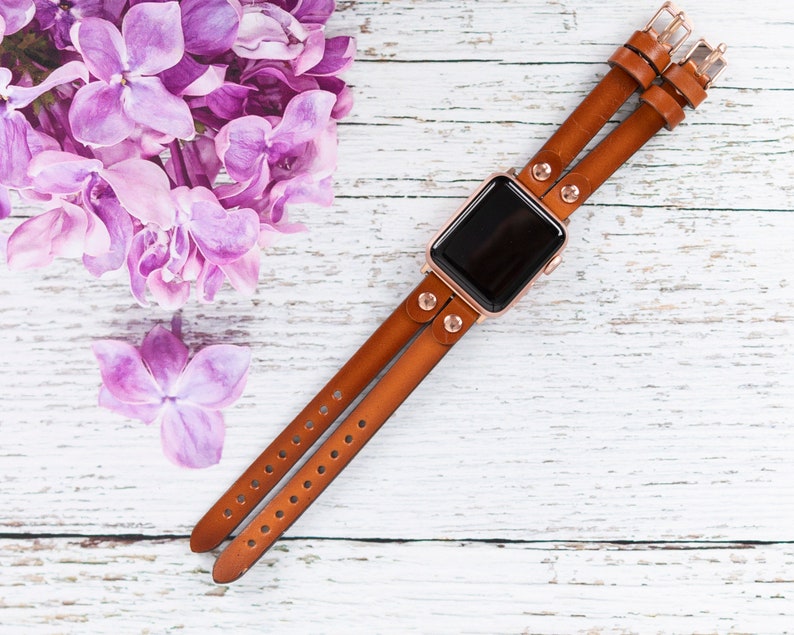 May include: A brown leather double-wrap watch band with rose gold hardware and a black watch face.