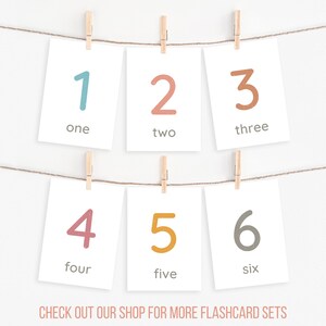 May include: Six flashcards with numbers 1 through 6, each with a different colour and the word for the number written below. The flashcards are hanging on a string with clothes pegs. The text at the bottom of the image reads "CHECK OUT OUR SHOP FOR MORE FLASHCARD SETS".