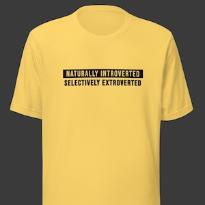May include: Yellow t-shirt with black text that reads "Naturally Introverted Selectively Extroverted".