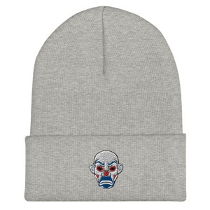 K&ouml;nnte beinhalten: Hellgraue Beanie-M&uuml;tze mit einem gestickten Clown-Gesicht. Der Clown hat rote Augen, einen blauen Mund und wei&szlig;es Make-up. Die M&uuml;tze ist aus weichem Strickmaterial gefertigt und hat einen gefalteten Saum. Ein stilvolles Accessoire f&uuml;r Fans der Figur.