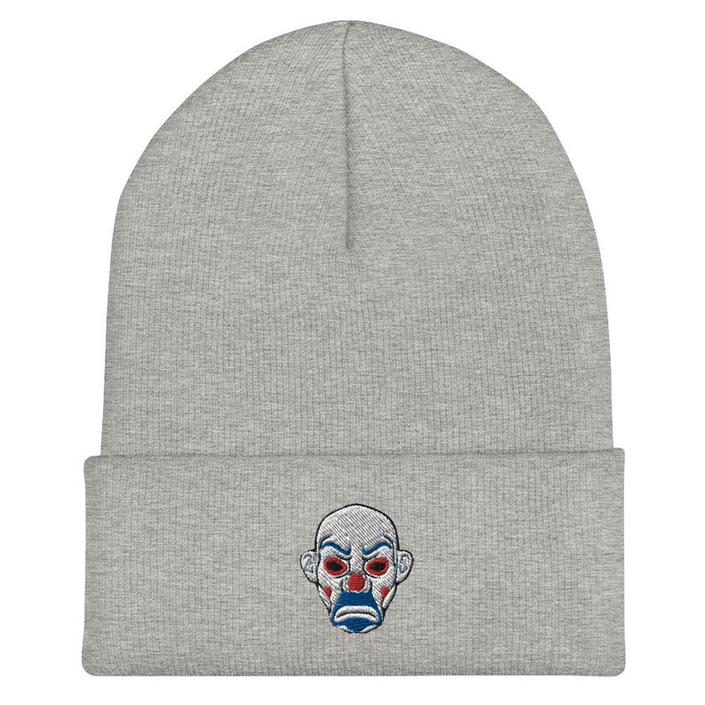 K&ouml;nnte beinhalten: Hellgraue Beanie-M&uuml;tze mit einem gestickten Clown-Gesicht. Der Clown hat rote Augen, einen blauen Mund und wei&szlig;es Make-up. Die M&uuml;tze ist aus weichem Strickmaterial gefertigt und hat einen gefalteten Saum. Ein stilvolles Accessoire f&uuml;r Fans der Figur.