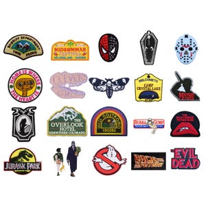 Può includere: Una collezione di toppe ricamate con vari disegni. Le toppe presentano immagini di film e programmi TV, tra cui una maschera di Spider-Man, una bara, una falena e loghi di "Jurassic Park", "Psycho" e "Evil Dead".