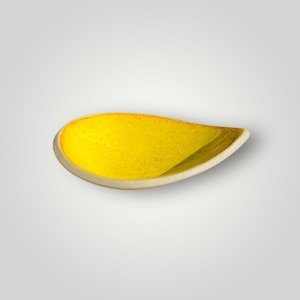 Peut inclure: Un bol en céramique en forme de goutte d'eau présentant un intérieur émaillé jaune vif et moucheté. Le bord extérieur et la base sont finis dans un ton blanc cassé ou beige clair mat contrastant, soulignant la forme organique et incurvée.