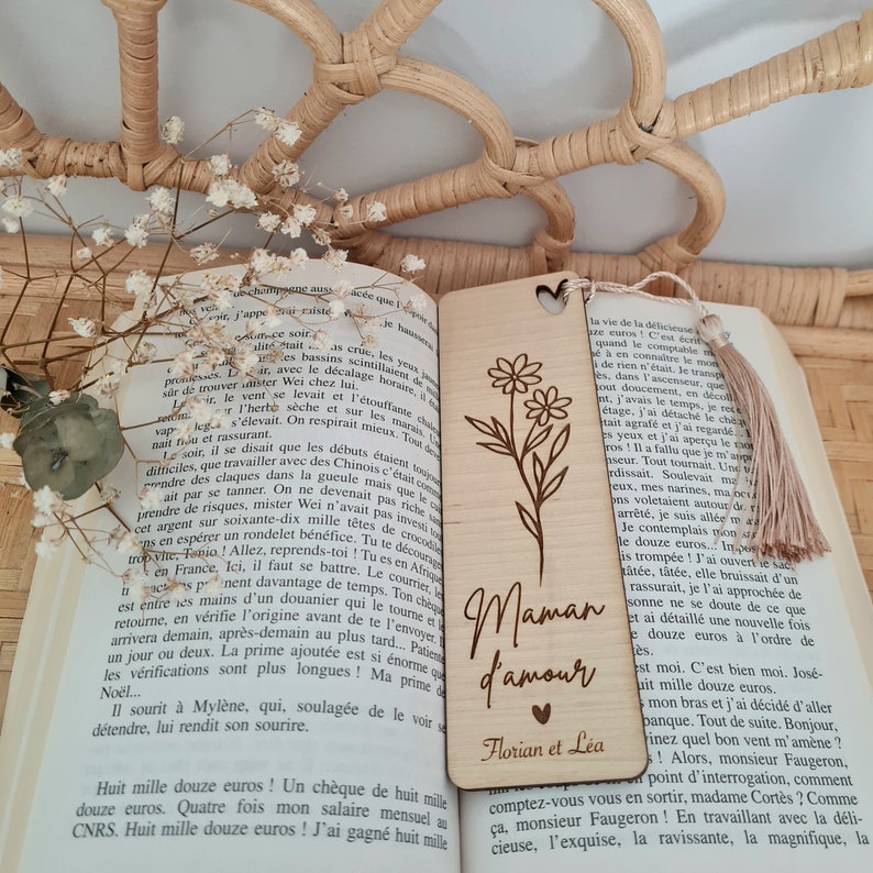 Puede incluir: Marcap&aacute;ginas de madera con forma de coraz&oacute;n y un dise&ntilde;o floral. El marcap&aacute;ginas est&aacute; grabado con el texto "Maman d'amour" y "Florian et Lea".
