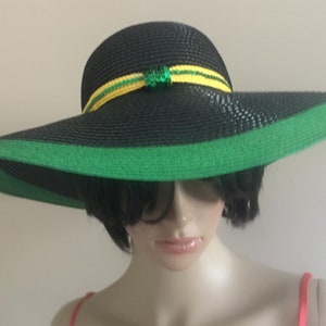 May include: A wide-brimmed black sun hat with a green trim and a yellow and green ribbon with sequins.