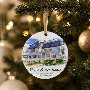 Puede incluir: Un adorno redondo de cer&aacute;mica blanca con una ilustraci&oacute;n en acuarela de una casa de dos pisos con techo oscuro. El texto "Home Sweet Home", "740 HARDING STREET" y "HOLLYWOOD FL" est&aacute; impreso en negro debajo de la casa. Cuelga de una cinta dorada.