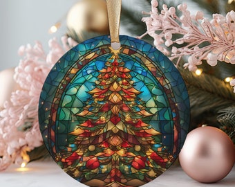 Puede incluir: Adorno navideño redondo con un diseño de vidriera que presenta un festivo árbol de Navidad. El árbol está representado en tonos cálidos de rojo, naranja y dorado, sobre un fondo azul y verde. Se adjunta una cinta dorada para colgarlo.