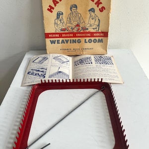 May include: A vintage Happy Folks Weaving Loom set including a red metal rectangular frame with notched edges, a metal weaving hook, an instructional booklet with blue diagrams, and a cardboard box featuring illustrations of people crafting.