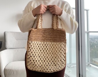 May include: A brown and cream crocheted tote bag with a wide, flat base and two handles. The bag is made of a thick, textured yarn and has a simple, classic design.