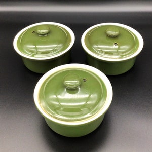 May include: Three green ceramic ramekins with lids. The ramekins have a white rim and a small hole in the lid.