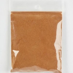 Peut inclure: Un sac en plastique transparent contenant une poudre brune. Le sac a un trou en haut pour l'accrocher.
