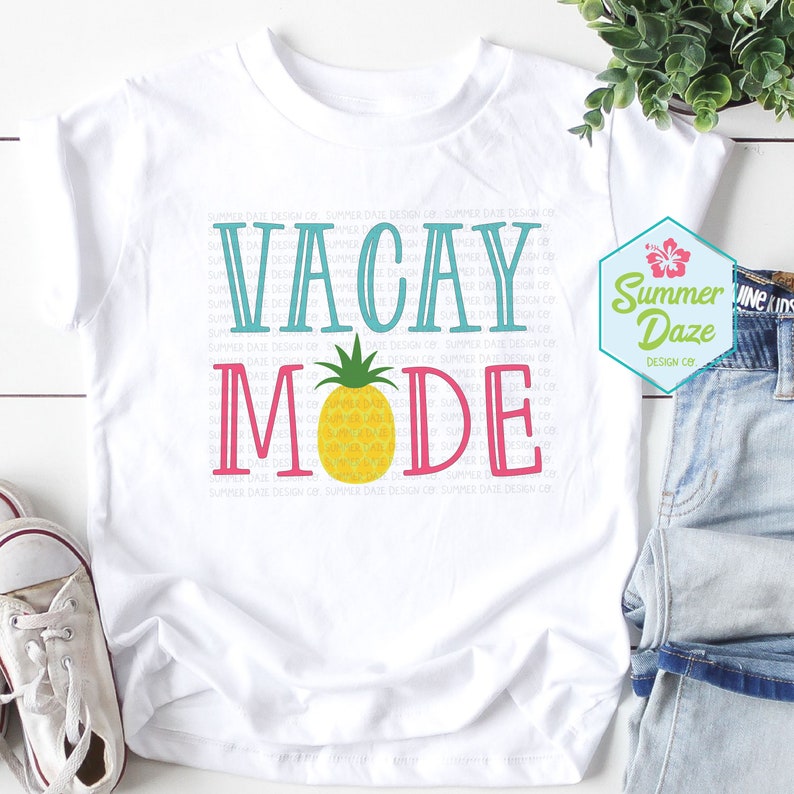 May include: White t-shirt with the text "VACAY MODE" in blue, pink, and white lettering. A yellow pineapple with green leaves is centered between the words. The text "Summer Daze Design Co." is in a small font at the bottom of the shirt.