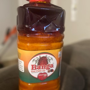 May include: A large plastic bottle of Banga Red Palm Oil. The bottle is red and clear, showing the orange oil inside. The label is yellow with green accents and features a palm tree and the text "Banga Red Palm Oil".