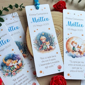 Könnte beinhalten: Drei Lesezeichen mit einer Aquarell-Illustration eines Prinzen und eines Fuchses. Die Lesezeichen sind weiß mit goldenen Sternen und blauem Text. Der Text auf den Lesezeichen lautet "Prima Comunione Matteo 25 Maggio 2025". Die Lesezeichen enthalten auch Zitate aus "Der kleine Prinz".