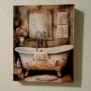 May include: A vintage-style bathroom with a white clawfoot bathtub with floral designs, a decorative mirror with an ornate frame, and towels hanging on a rack.