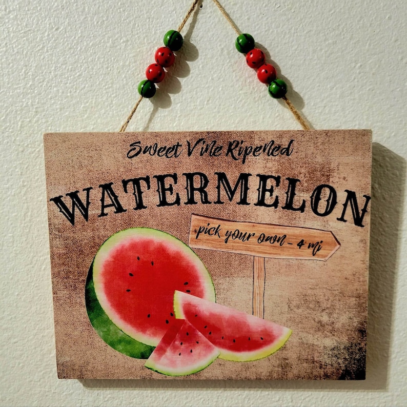 Pode incluir: Uma placa de madeira r&uacute;stica com o texto "Sweet Vile Ripened Watermelon pick your own - 4 mi" e uma ilustra&ccedil;&atilde;o em aquarela de fatias de melancia.